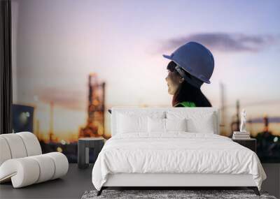 Asian woman petrochemical engineer working at night with digital tablet Inside oil and gas refinery plant industry factory at night for inspector safety quality control.. Wall mural