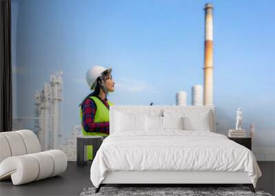 Asian woman petrochemical engineer working at night with laptop Inside oil and gas refinery plant industry factory at night for inspector safety quality control.. Wall mural