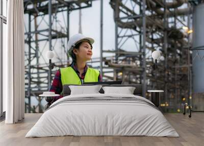 Asian woman petrochemical engineer working at night with laptop Inside oil and gas refinery plant industry factory at night for inspector safety quality control.. Wall mural