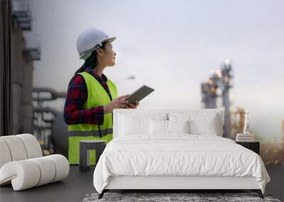 Asian woman petrochemical engineer working with digital tablet Inside oil and gas refinery plant industry factory for inspector safety quality control.. Wall mural