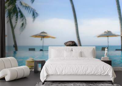 Summer travel vacation concept, Traveler asian man with coconut relax in luxury infinity pool hotel resort with sea beach and palm tree background Wall mural