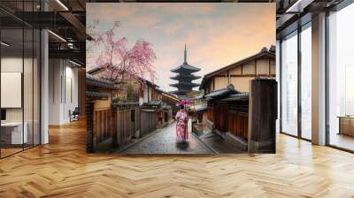 woman traveller wearing japanese traditional kimono with red umbrella sightseeing at famous destination Sannen Zaka Street with historical building house with cherry blossom in spring, Kyoto, Japan. Wall mural