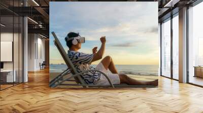 Young Asian man using virtual reality glasses for business meeting on the tropical beach over beautiful sea and sky background Wall mural