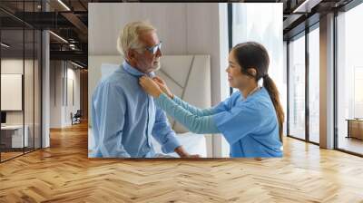 young asian woman nurse helping get dress to disabled elderly man in bed at retirement home. millenn Wall mural