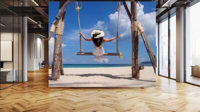 Happy young woman enjoy and sway the wooden swing over the sea beach, blue sky and cloud. Tourist women relax and enjoy with wood swing on the beach Phuket, Thailand. Summer holiday vacition concept. Wall mural