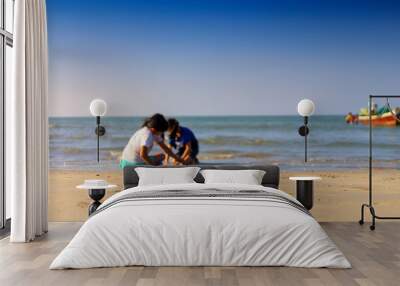 Holiday concept. 2 gril play sand on the beach with clear sky background. Wall mural