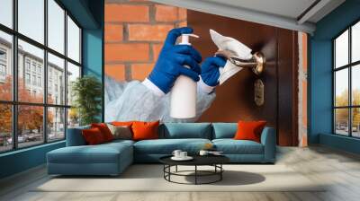 Woman cleaning a door handle with a disinfection spray and disposable wipe Wall mural