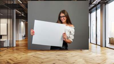 Beautiful woman holding a blank billboard isolated on gray background - inage Wall mural