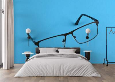 Reading glasses isolated on blue background. Glasses hang in air Wall mural