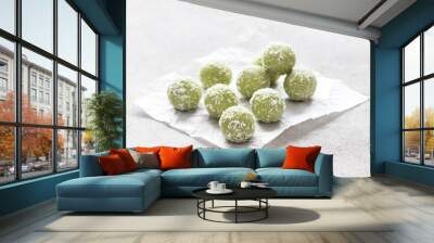 Dessert balls of cottage cheese with the addition of green tea matcha in coconut chips on paper on a light gray background Wall mural