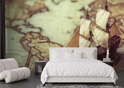 A model ship rests on a detailed map of the world, showcasing timeless charm and the spirit of exploration. The combination of the old ship and map invites viewers to appreciate the magnificence of Wall mural