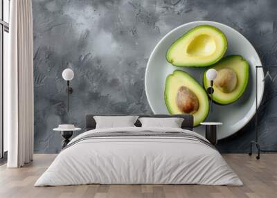 Avocado halves displayed on a white dish against a gray backdrop Room for text Bird s eye view Wall mural