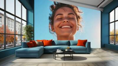 Fit young woman smiles while deep breathing in front of a clear blue sky on a sunny and windy summer day. Wall mural