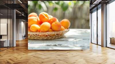 Fresh apricots in a wicker bowl displayed on a white wooden table outdoors Wall mural