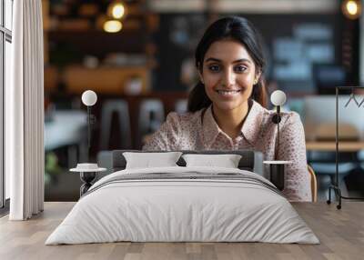 Happy and accomplished female Indian programmer working in a contemporary office, providing tech support by typing on her laptop with a smile. Wall mural