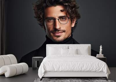 In the studio a stylish and sophisticated man with curly hair is portrayed in fashion donning a black turtleneck and glasses against a gray backdrop Wall mural