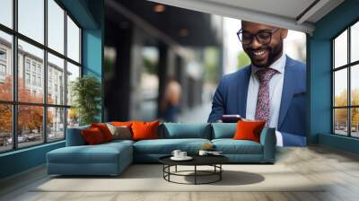 Joyful African executive utilizing cellphone in urban setting. Wall mural