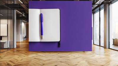 Notebook open with pen on purple surface Wall mural