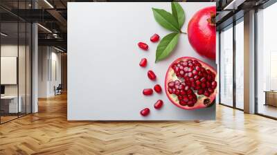 Fresh pomegranate fruits with vibrant red seeds and green leaves Wall mural