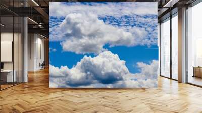 The fluffy clouds in the bright blue sky. Wall mural