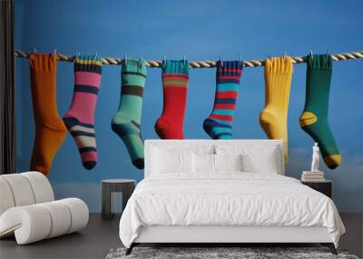 Colorful socks dancing in the breeze on a bright, sunny day against a picturesque sky filled with soft, fluffy clouds Wall mural