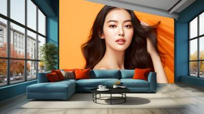 Portrait of a beautiful, sexy, smiling Asian woman with perfect skin, orange background, banner. Wall mural