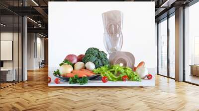 Two piece ostomy appliance including flange and pouch surrounded by various vegetables Wall mural