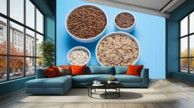 brown rice, buckwheat, flax and oat flakes in white cups on a blue background Wall mural