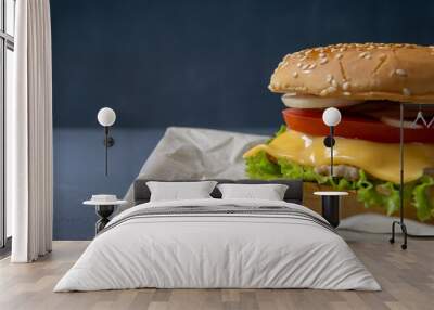 Burger with beef patty, salad, a slice of tomato and cheese, onions and sauce with paprika in a grilled bun with sesame Wall mural