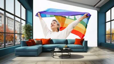 Low angle view of a old woman holding waving LGBT flag over head.  LGBT concept and old age.  white background Wall mural