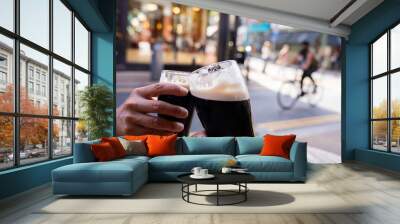 Close-up of two hands toasting each other with Guinness beers on a central Dublin street having a good time on a beautiful autumn morning Wall mural