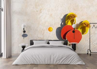 Two ping pong racket and two yellow flip flop just as a ball bounces on the ground. Wall mural