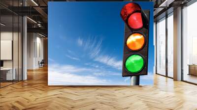 Closeup of a traffic light on a blue sky with clouds and copy space, with all three lights on, green, orange and red. Italy, Europe. Wall mural