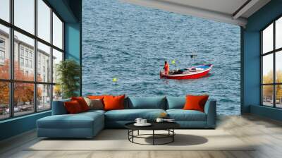 Fisherman on a small red fishing boat between the waves of the sea. Liguria, Italy Wall mural