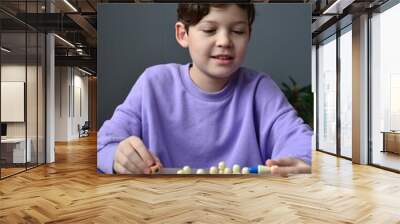 A cute boy in purple sweatshirt is playing memory chess. Wall mural