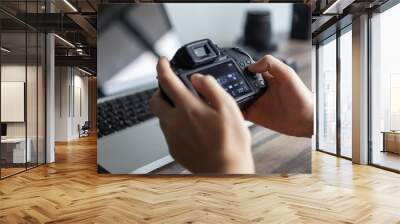 Photographer or stock photography concept, digital black camera in hands near laptop close up Wall mural