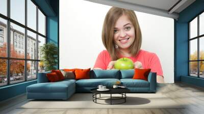 Portrait photo of smiling pretty girl with bob hairstyle holding green apple in both hands as if suggesting it, healthy lifestyle or fruit diet. White background Wall mural