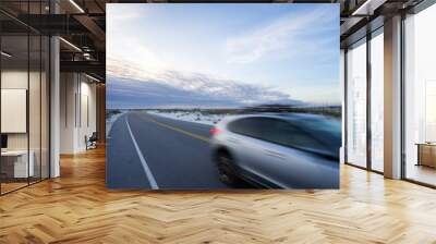 A fast car driving on a beach road during sunset Wall mural