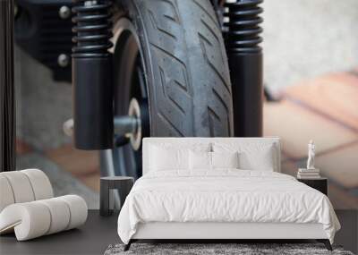 Close up to a front carved wheel of a black electric scooter with front suspension Wall mural