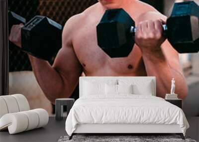 fitness guy doing exercises with dumbbells outdoors Wall mural