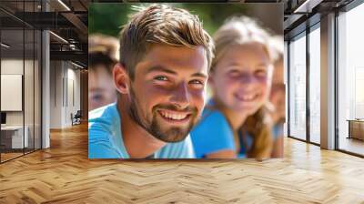 Smiling young man with children outdoors Wall mural