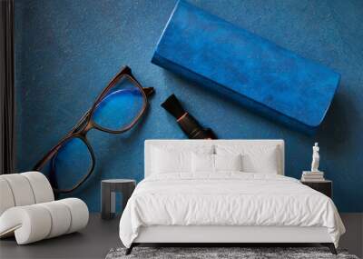 Glasses, glasses case and cleaning handle for optics,  on blue background, top view, shallow depth of sharpness Wall mural