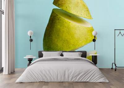 A juicy and ripe fresh pear cut into levitating slices isolated on pastel blue background. Sweet and healthy summer and autumn fruit. Minimal organic and vegan diet backdrop. Creative food concept. Wall mural