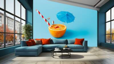 Summer layout with miniature people surfing and swimming on orange against vibrant blue background. Creative vacation concept. Minimal tropical cocktail, exotic juice bar or sea activity banner. Wall mural