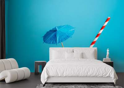 Summer layout with orange, straw and umbrella on vibrant blue background. Creative vacation concept. Minimal tropical cocktail, exotic fruit, juice or food banner. Wall mural