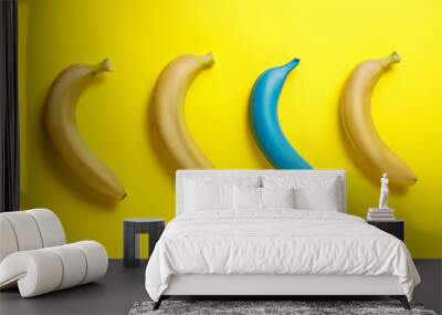 Yellow bananas in the row with one blue painted banana on vibrant yellow background. Minimal summer food concept. Geometrical fruit composition. Flat lay, top view. Wall mural