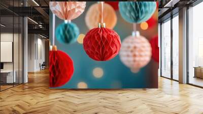 Colorful paper decorations in red, turquoise, and cream hanging against a blurred background with soft lights, creating a festive atmosphere. Wall mural