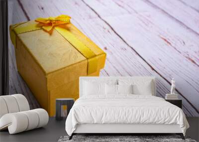 Yellow gift box with bow ribbon on the white wooden background, birthday, Christmas, Valentine day concept. Wall mural