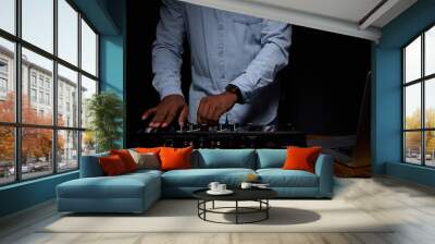 African American stylishly dressed man in DJ booth. On black background in the frame, only the body, close up. Professional DJ equipment and laptop on the table. On hand is a modern smart watch. Wall mural