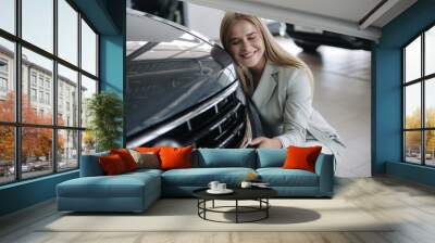 Business woman chossing a new car in a car showroom. Happy female hug new car and very glad. Elegant female in suit Wall mural